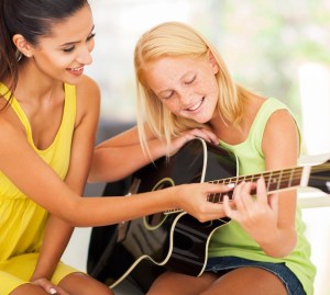 cropped-guitar-teacher-female-bigstock-smiling-beautiful-music-teache-46068454.jpg